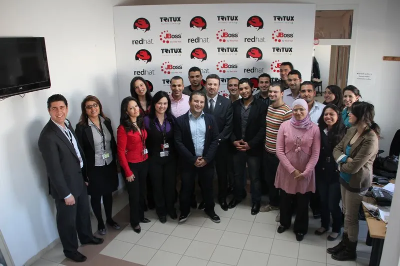 The Tritux team of about twenty people posing in front of the Red Hat, JBoss and Tritux backdrop, with Malik Saheb in a tie in the middle